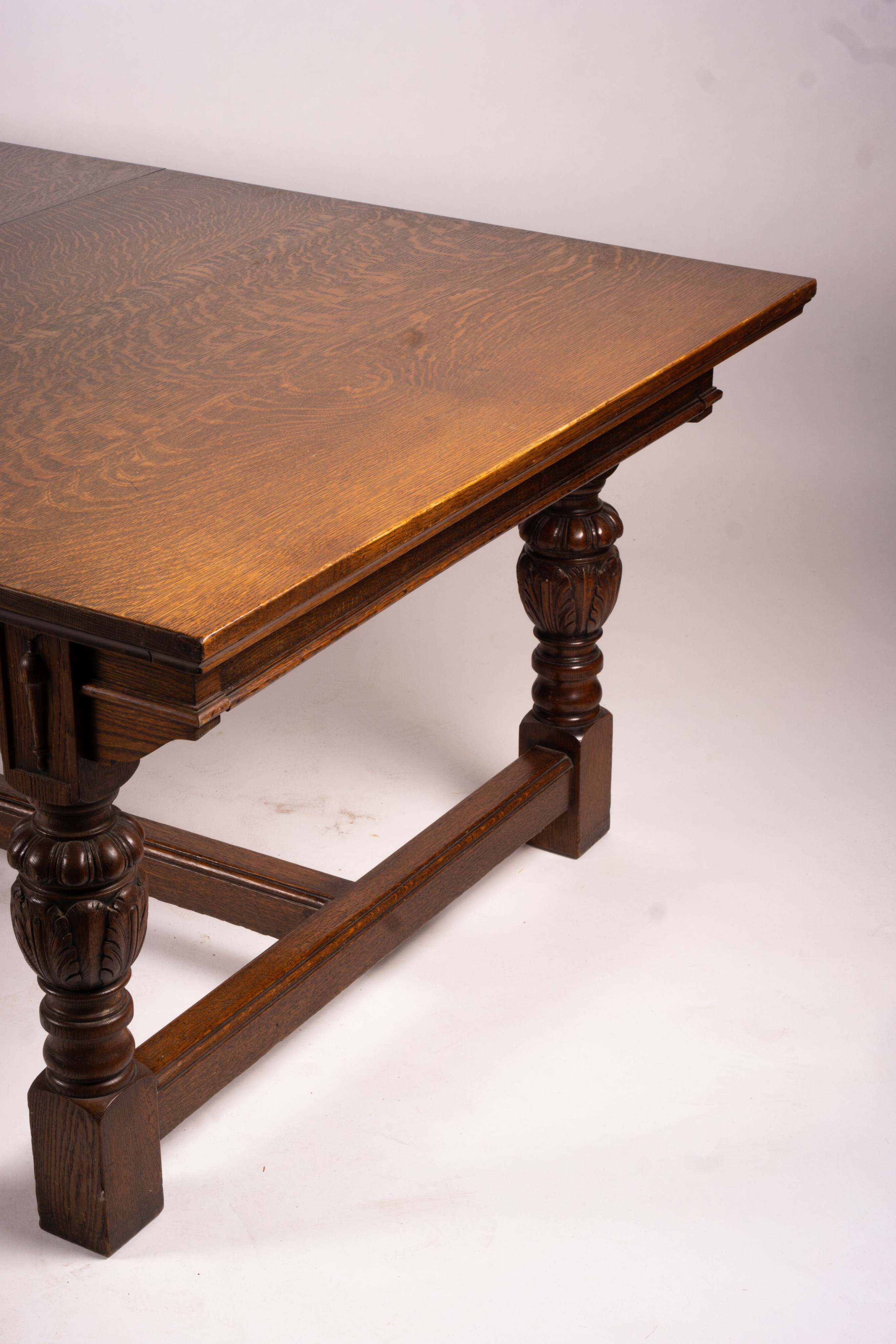 A 17th century style carved rectangular oak extending dining table with 'H' stretcher, 300cm extended, two spare leaves, width 121cm, height 75cm